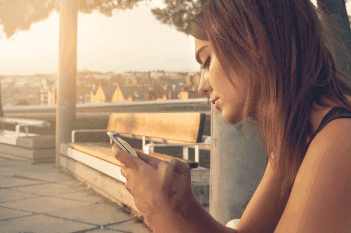 Person looking down at phone with slouched posture, showing signs of tech neck