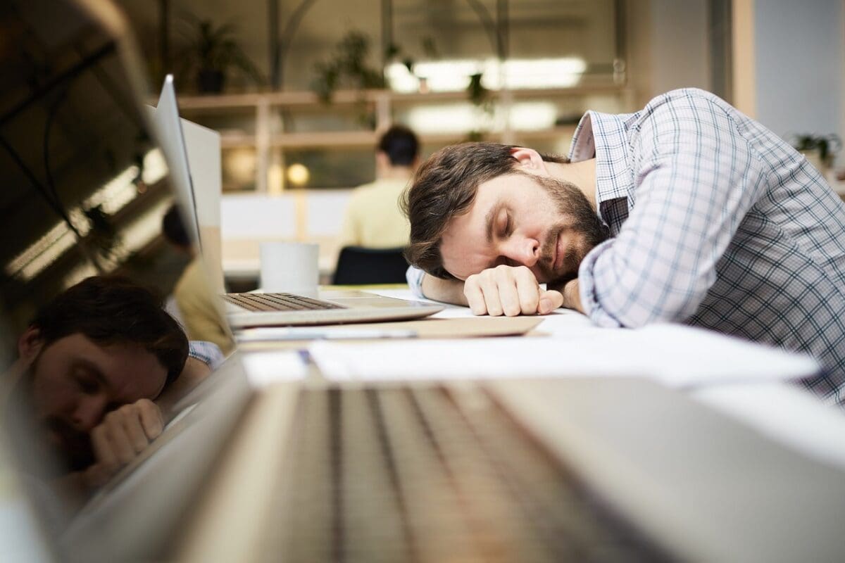 Tired man sleeping at his desk due to fatigue before acupuncture treatment in Edmonton